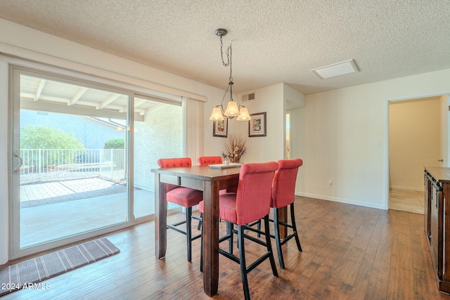 dining space with a textured ceiling and dark hardwood / wood-style floors