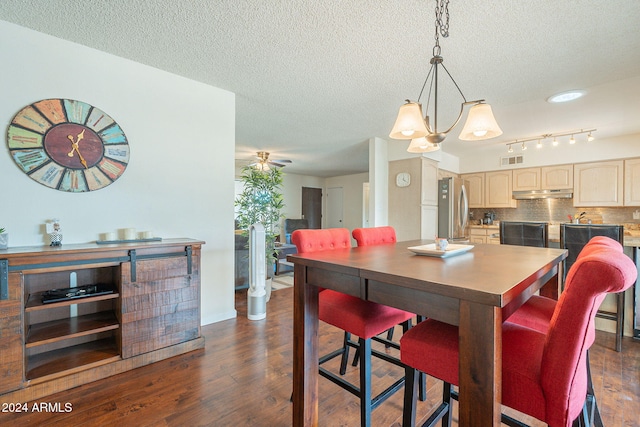 dining space with dark wood-type flooring, ceiling fan with notable chandelier, and a textured ceiling