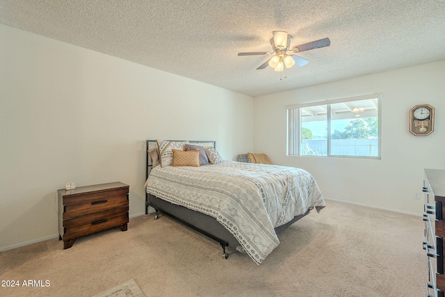 bedroom featuring a textured ceiling, light colored carpet, and ceiling fan