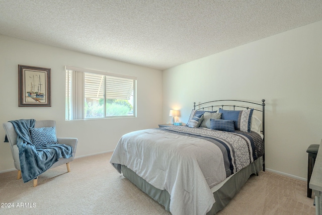 bedroom with light colored carpet and a textured ceiling