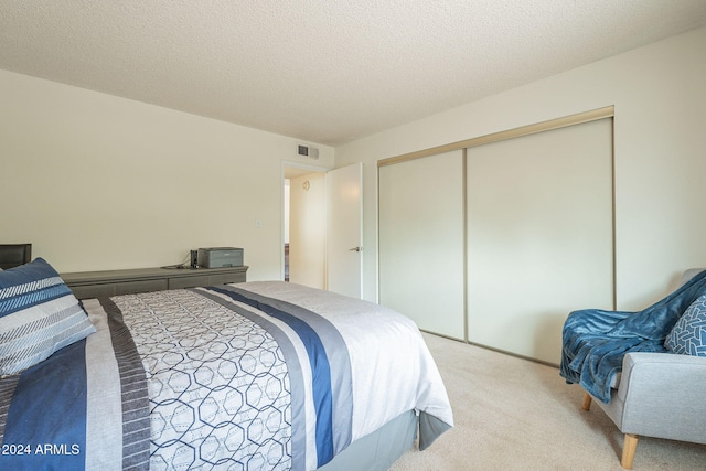 carpeted bedroom with a textured ceiling and a closet