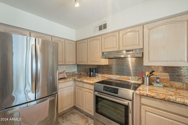 kitchen with stainless steel appliances, light stone counters, light brown cabinets, a textured ceiling, and backsplash