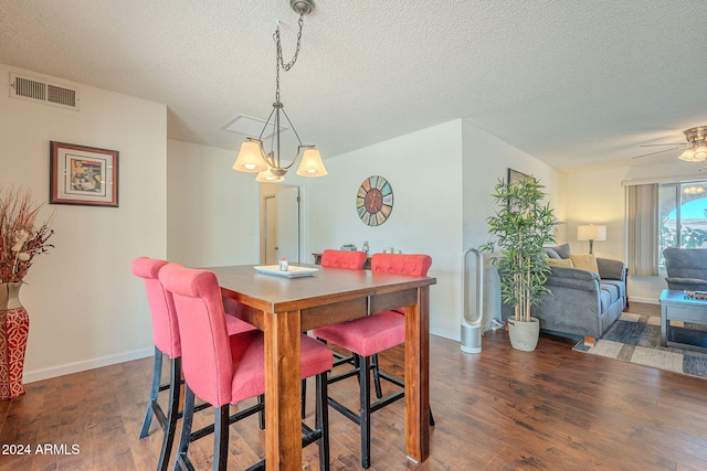 dining room with ceiling fan with notable chandelier, dark wood-type flooring, and a textured ceiling