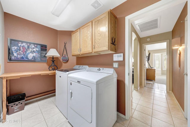 washroom with cabinet space, washing machine and clothes dryer, light tile patterned floors, and baseboards