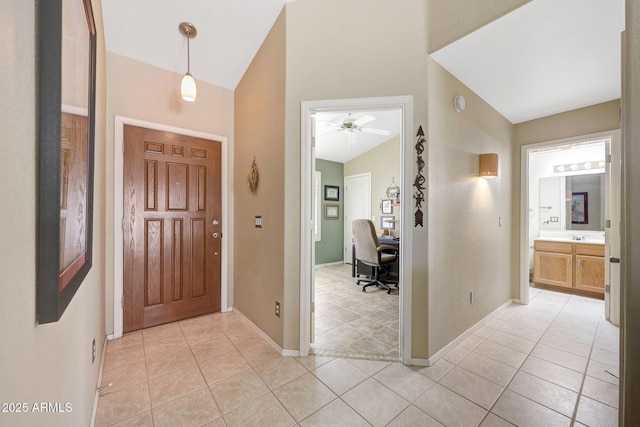foyer entrance featuring light tile patterned floors, a ceiling fan, baseboards, and vaulted ceiling