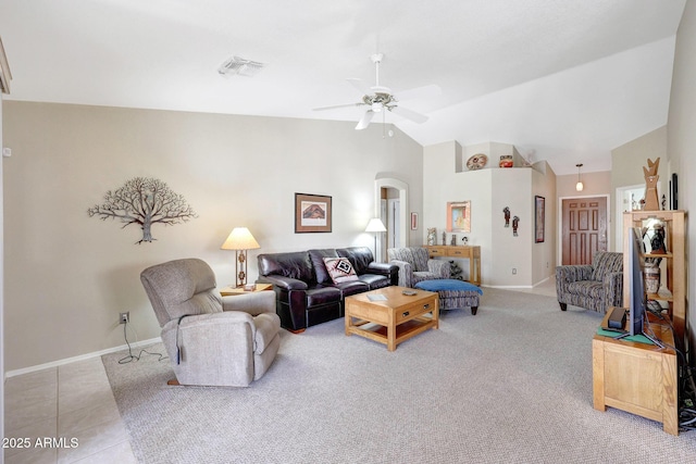 living area featuring arched walkways, a ceiling fan, vaulted ceiling, baseboards, and light colored carpet