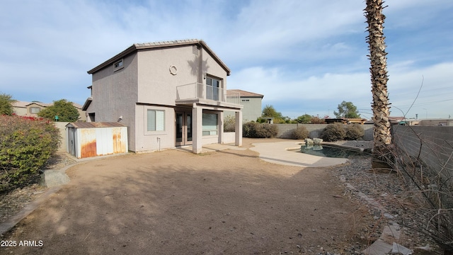 back of property with a patio area, a balcony, and a shed