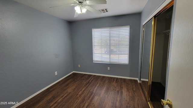 unfurnished bedroom featuring ceiling fan, a closet, and dark wood-type flooring