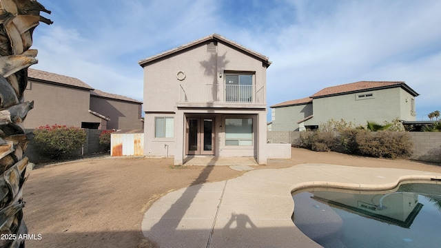 back of property with french doors, a patio, a balcony, and a fenced in pool