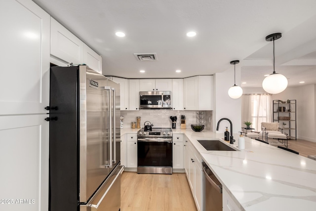 6835 E Friess Dr, Scottsdale, AZ 85254 - kitchen featuring stainless steel appliances, a sink, light wood finished floors, white cabinets, and recessed lighting