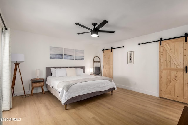 6835 E Friess Dr, Scottsdale, AZ 85254 - bedroom with a barn door, light wood-type flooring, baseboards, and a ceiling fan
