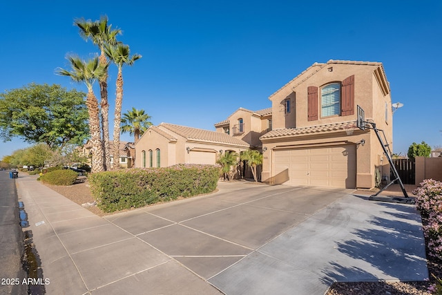 mediterranean / spanish home featuring a garage, concrete driveway, a tiled roof, and stucco siding