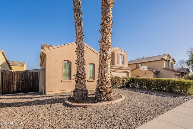 mediterranean / spanish-style home with fence and stucco siding