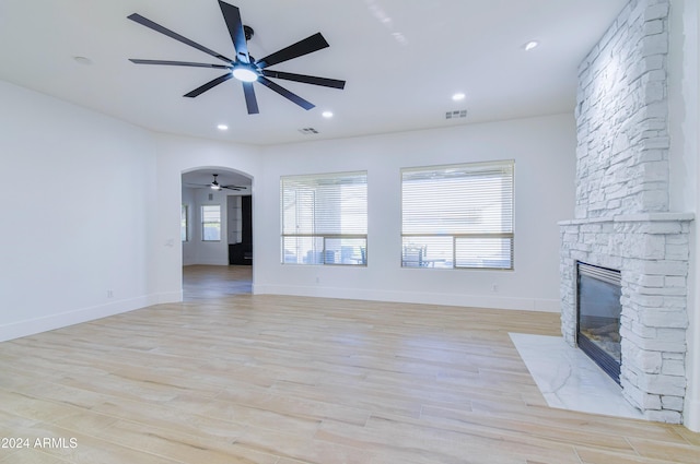 unfurnished living room with light hardwood / wood-style flooring and a stone fireplace