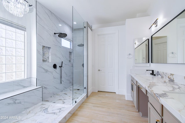 bathroom featuring plenty of natural light, a tile shower, and vanity