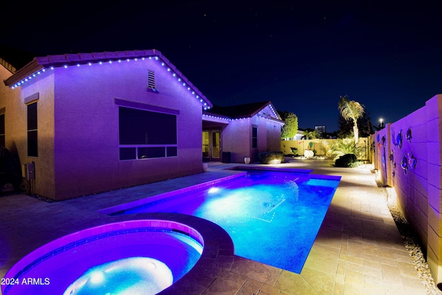 pool at twilight with an in ground hot tub and a patio