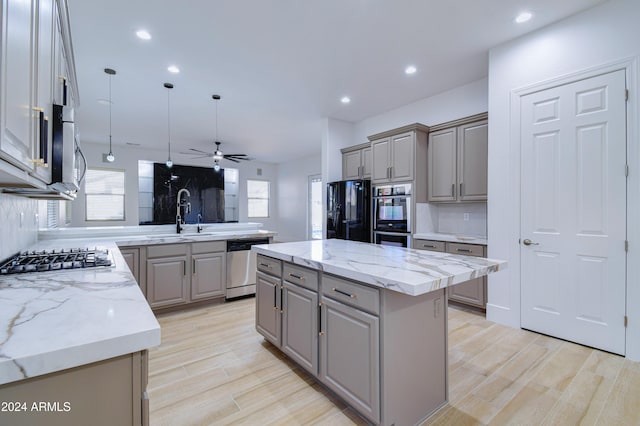 kitchen with a center island, sink, hanging light fixtures, tasteful backsplash, and stainless steel appliances