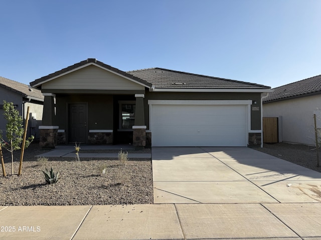 view of front facade featuring a garage, stone siding, driveway, and a tiled roof