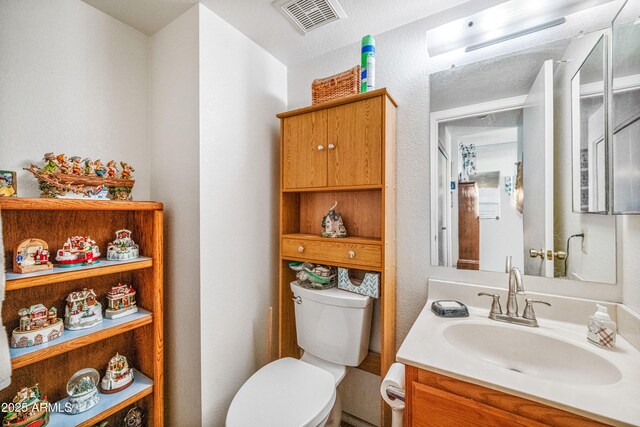 half bathroom with toilet, visible vents, and vanity