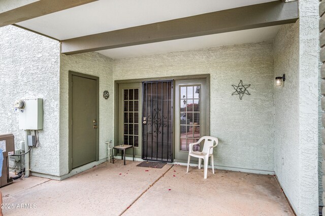 entrance to property with stucco siding and a patio area