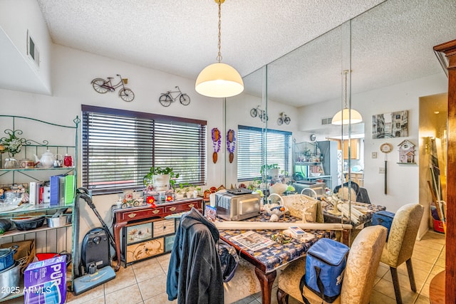 dining room with visible vents, light tile patterned floors, and a textured ceiling