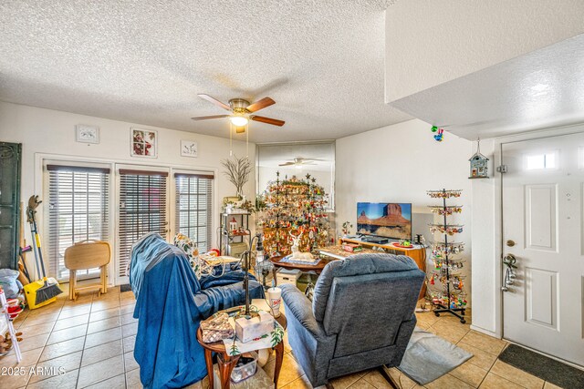 living area with a textured ceiling, a ceiling fan, and light tile patterned flooring