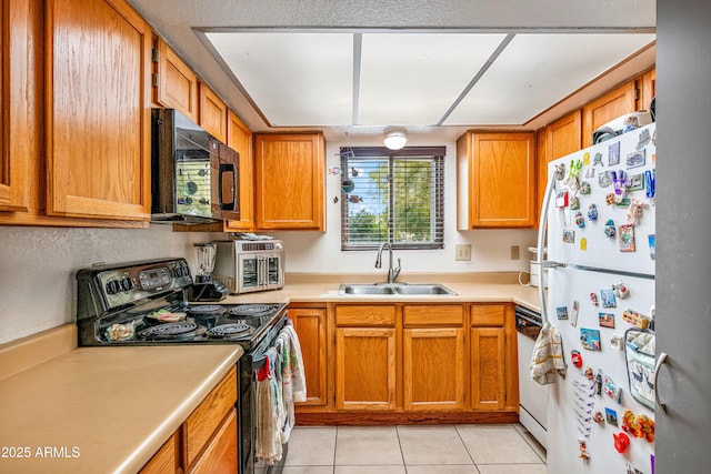 kitchen featuring light tile patterned floors, brown cabinets, a sink, light countertops, and black appliances