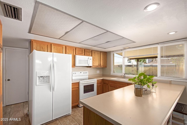 4145 W Hayward Ave, Phoenix, AZ 85051 - kitchen with white appliances, a sink, a peninsula, light countertops, and brown cabinets