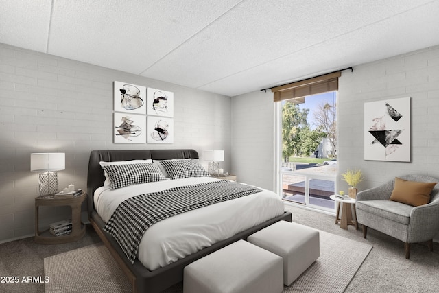 bedroom featuring carpet, access to exterior, a textured ceiling, and brick wall