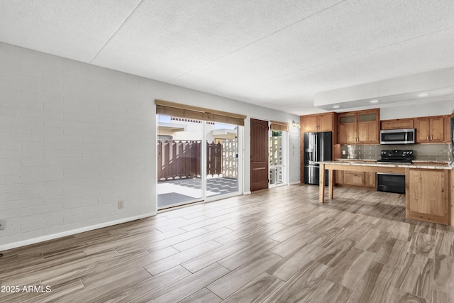 kitchen with light wood-type flooring, stainless steel appliances, and tasteful backsplash