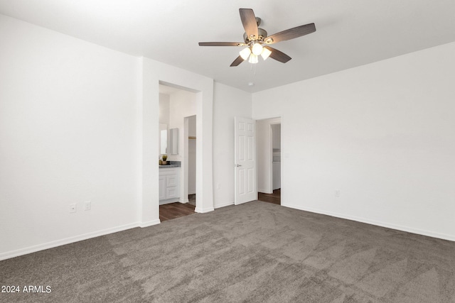 unfurnished bedroom with ensuite bath, dark colored carpet, and ceiling fan