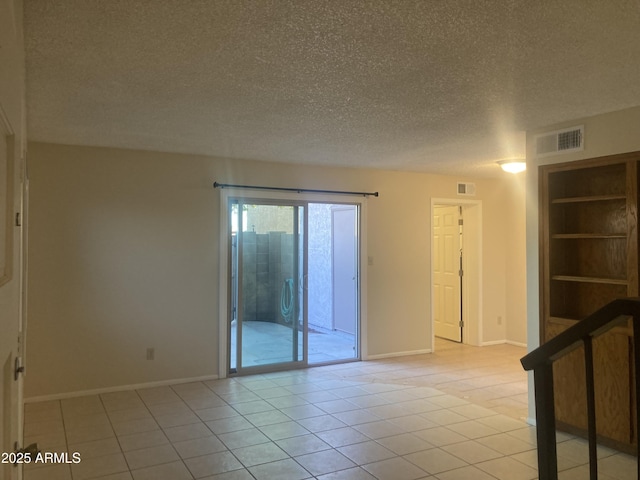 unfurnished room featuring built in shelves, a textured ceiling, and light tile patterned floors