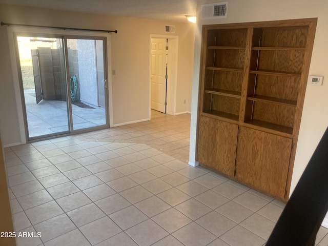 unfurnished room with light tile patterned floors and built in shelves