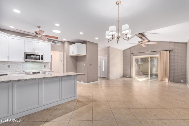 kitchen featuring brick wall, ceiling fan with notable chandelier, appliances with stainless steel finishes, and lofted ceiling with beams