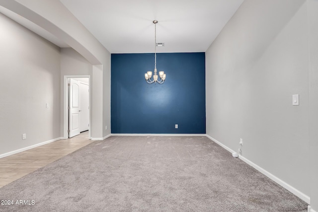 carpeted spare room featuring a notable chandelier