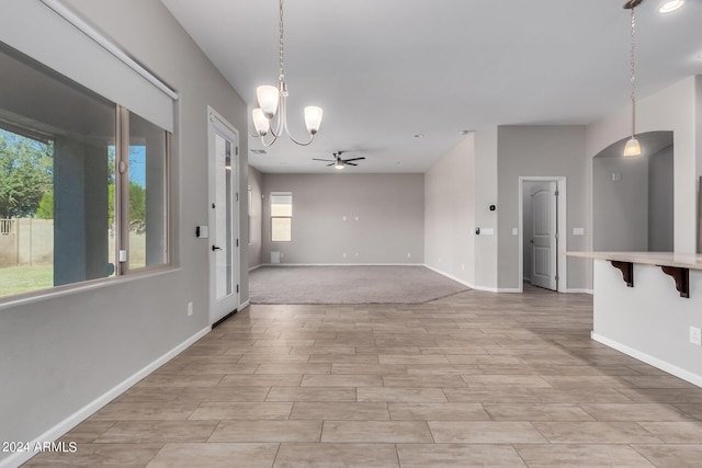 spare room featuring ceiling fan with notable chandelier