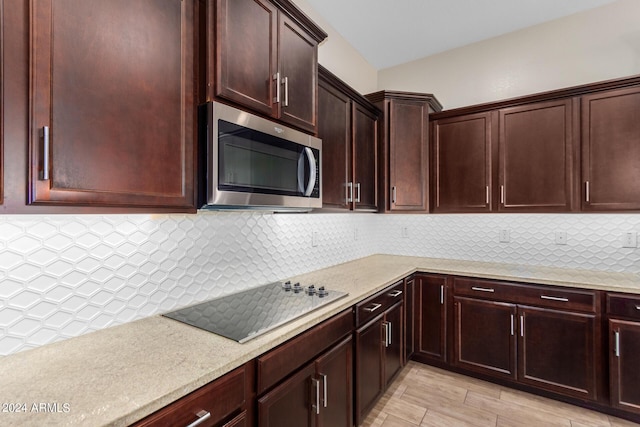 kitchen with black electric stovetop and tasteful backsplash