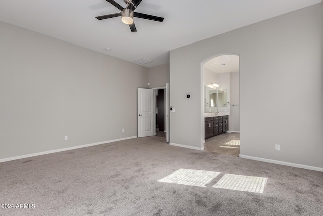 unfurnished bedroom with light carpet, ensuite bathroom, and ceiling fan
