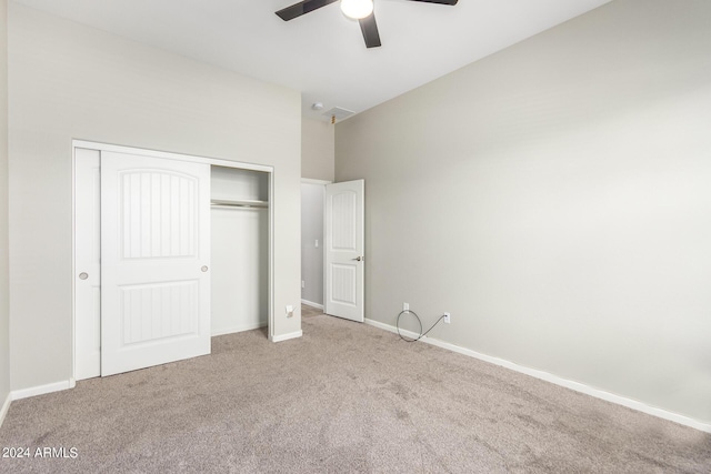 unfurnished bedroom with ceiling fan, a closet, a towering ceiling, and light colored carpet