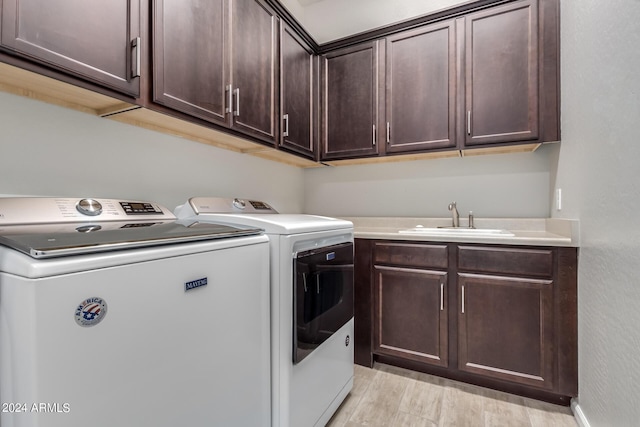 laundry area featuring cabinets, separate washer and dryer, sink, and light hardwood / wood-style flooring