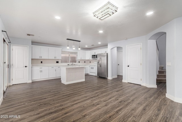 kitchen featuring stainless steel fridge, arched walkways, stove, light countertops, and a sink