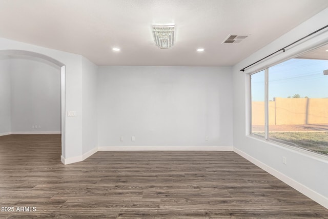 unfurnished room featuring baseboards, visible vents, arched walkways, dark wood-style flooring, and recessed lighting