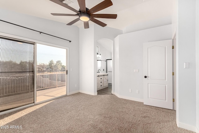 unfurnished bedroom featuring baseboards, arched walkways, ensuite bath, carpet, and access to outside