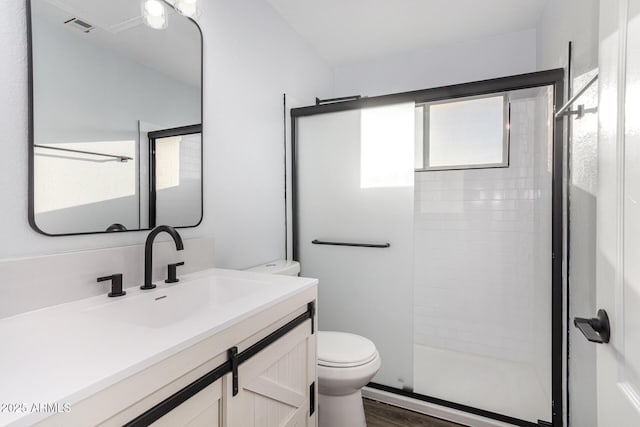 full bathroom featuring visible vents, toilet, wood finished floors, vanity, and a shower stall