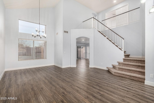 unfurnished living room featuring dark wood-type flooring, stairway, visible vents, and baseboards