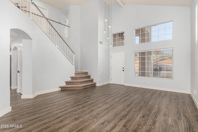 foyer entrance featuring baseboards, dark wood finished floors, and arched walkways