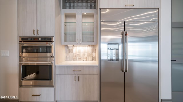 kitchen featuring stainless steel appliances, light brown cabinetry, and decorative backsplash