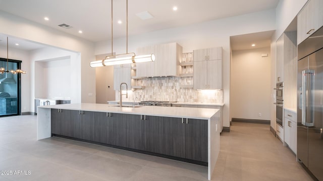 kitchen with sink, decorative backsplash, hanging light fixtures, stainless steel appliances, and a spacious island