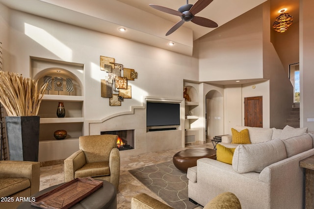 living room with ceiling fan, built in features, and lofted ceiling