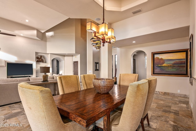 dining room featuring built in shelves, a towering ceiling, and a chandelier